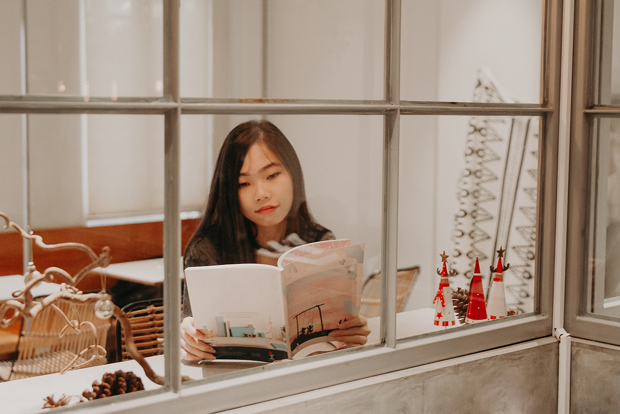 窓際で雑誌を読む女性